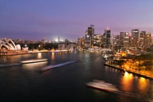 Overview of Sydney with the Opera House in the left corner. Living in Sydney is costly